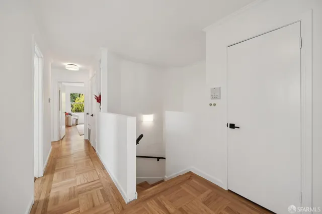 a view of a hallway with wooden floor and a living room