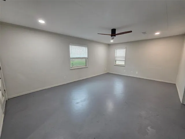 an empty room with windows and fireplace