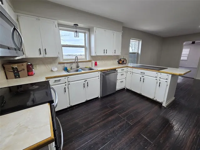 a kitchen with white cabinets stainless steel appliances a sink and a window