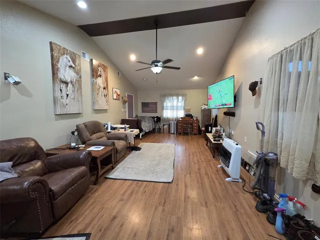 a living room with furniture kitchen view and a wooden floor