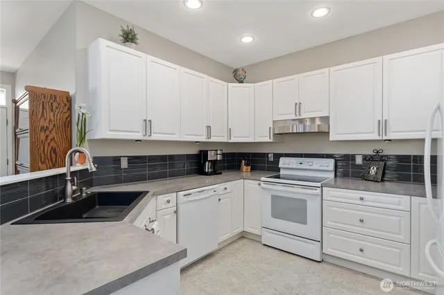 a kitchen with white cabinets and sink