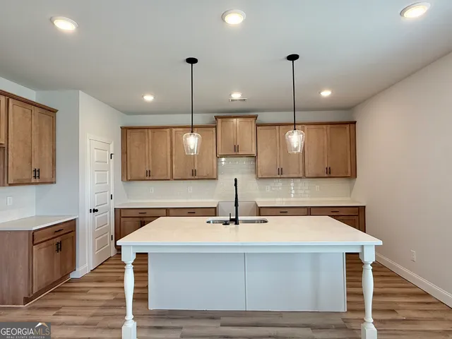 a kitchen with kitchen island a sink stainless steel appliances and chairs
