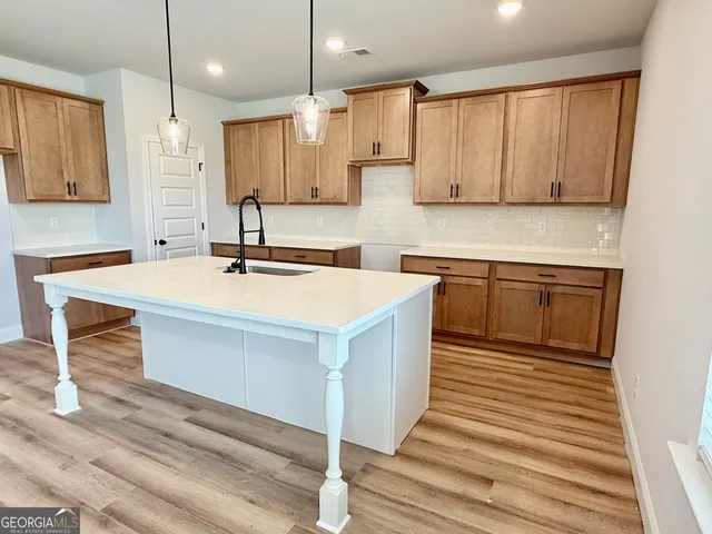 a kitchen with stainless steel appliances a stove a sink a center island and cabinets