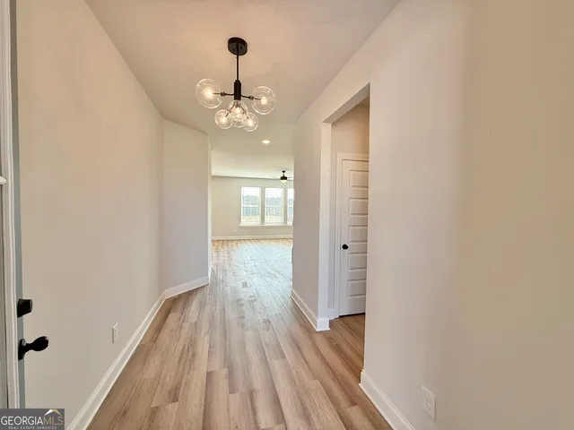a view of a hallway with wooden floor and chandelier