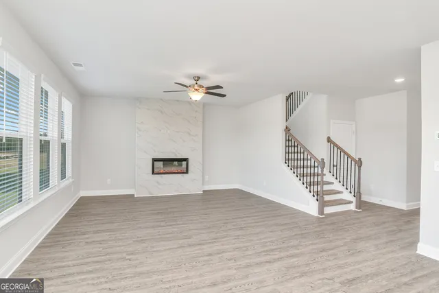 a view of an empty room with a window and kitchen view