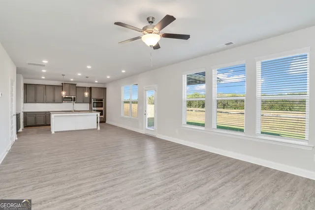 a view of a kitchen with a refrigerator a ceiling fan and wooden floor