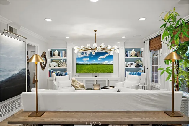 a living room with fireplace kitchen view and a chandelier