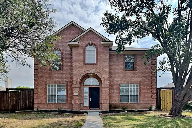 a front view of a house with a yard garage and tree