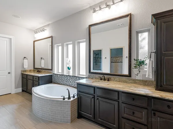 a large white bathroom with a granite countertop double vanity sink a mirror and a bathtub