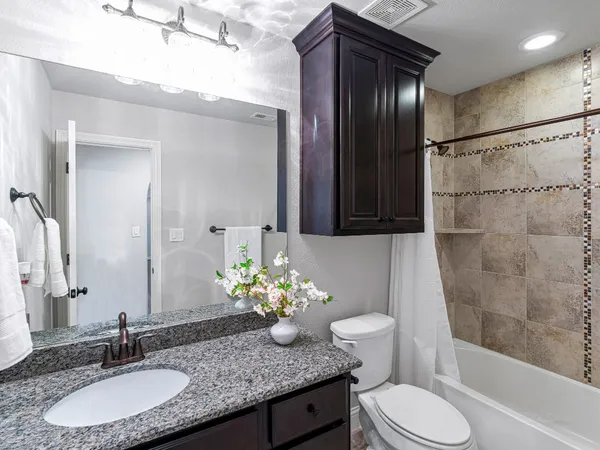 a bathroom with a granite countertop bathtub sink vanity mirror and toilet