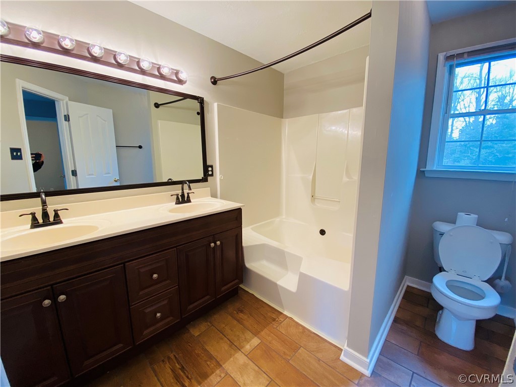 6956 Fox Drive Prince George, VA 23875 - Photo 11 of 26 a bathroom with a double vanity sink a toilet and a large mirror