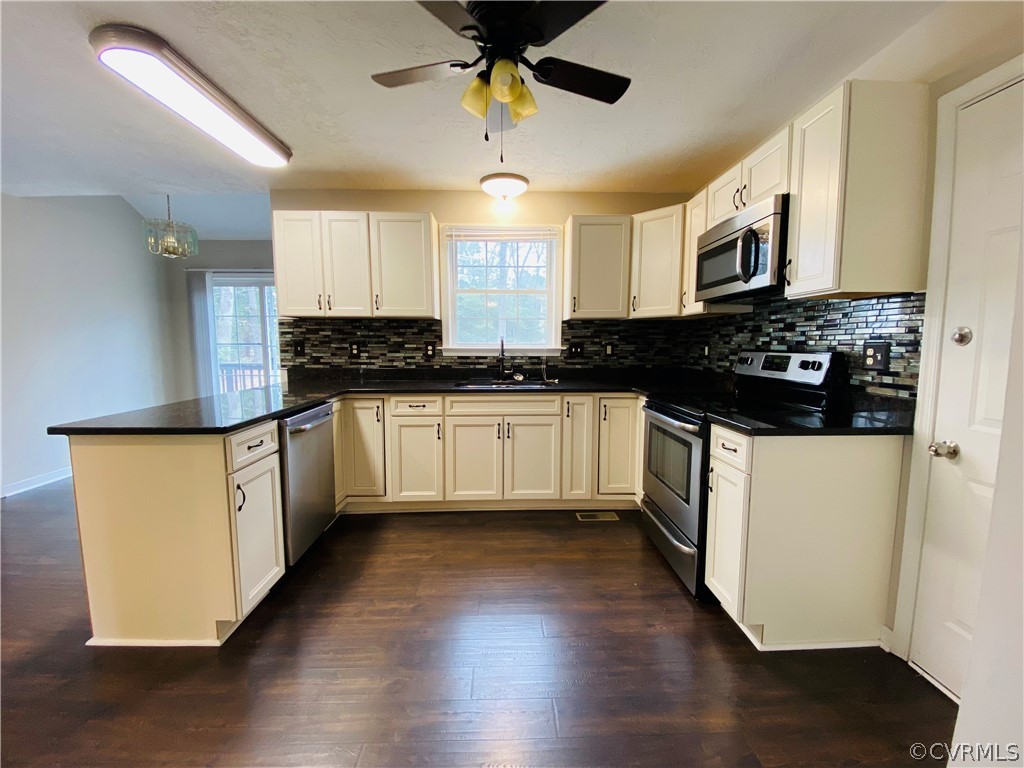 6956 Fox Drive Prince George, VA 23875 - Photo 8 of 26 a kitchen with granite countertop a stove a sink a refrigerator and white cabinets with wooden floor