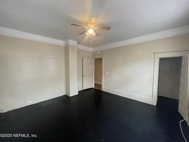 an empty room with wooden floor fan and windows