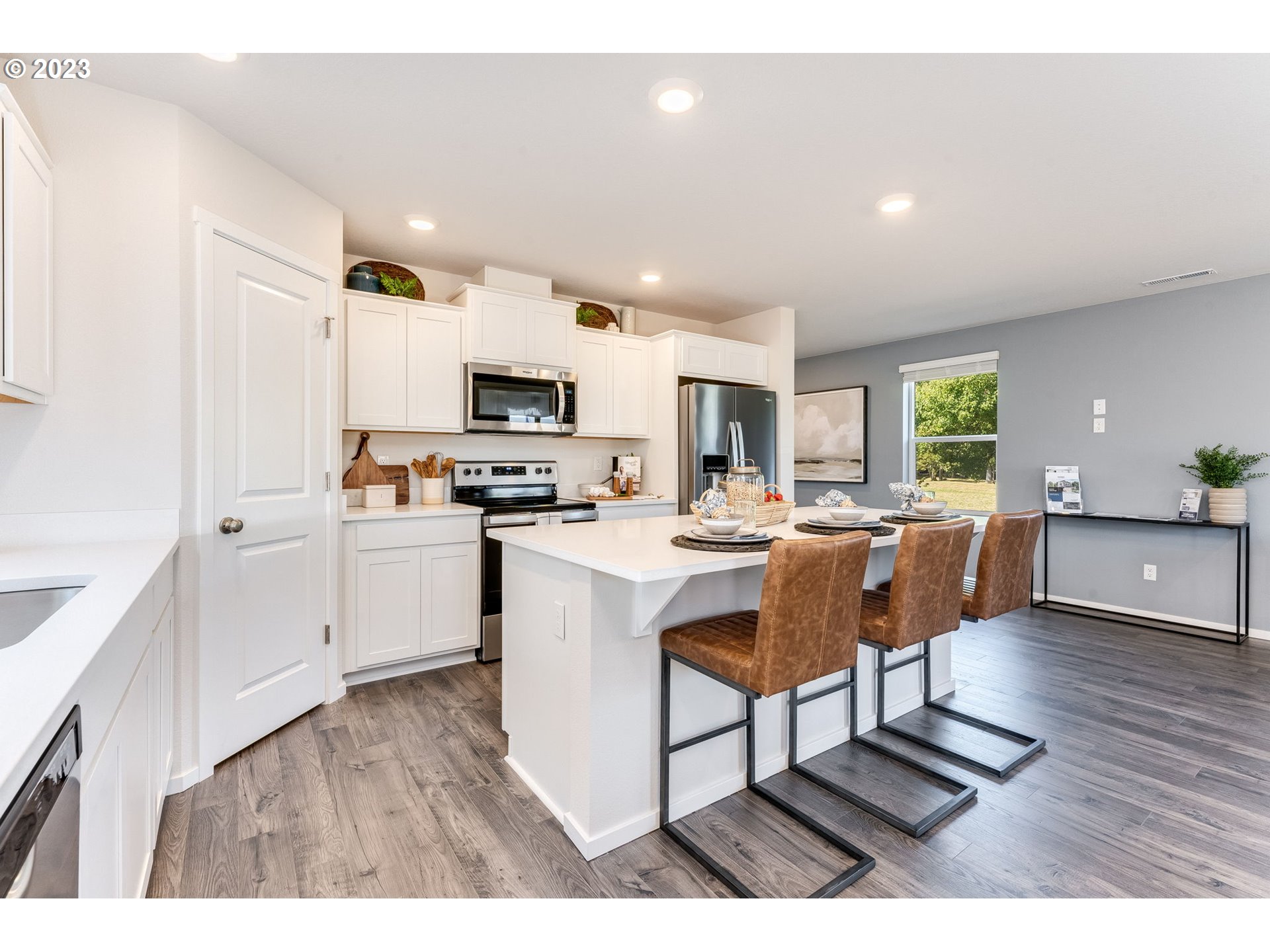 17413 Northwest 10th Avenue Ridgefield, WA 98642 - Photo 5 of 27 a kitchen with stainless steel appliances kitchen island granite countertop a refrigerator a stove a sink a dining table and chairs with wooden floor