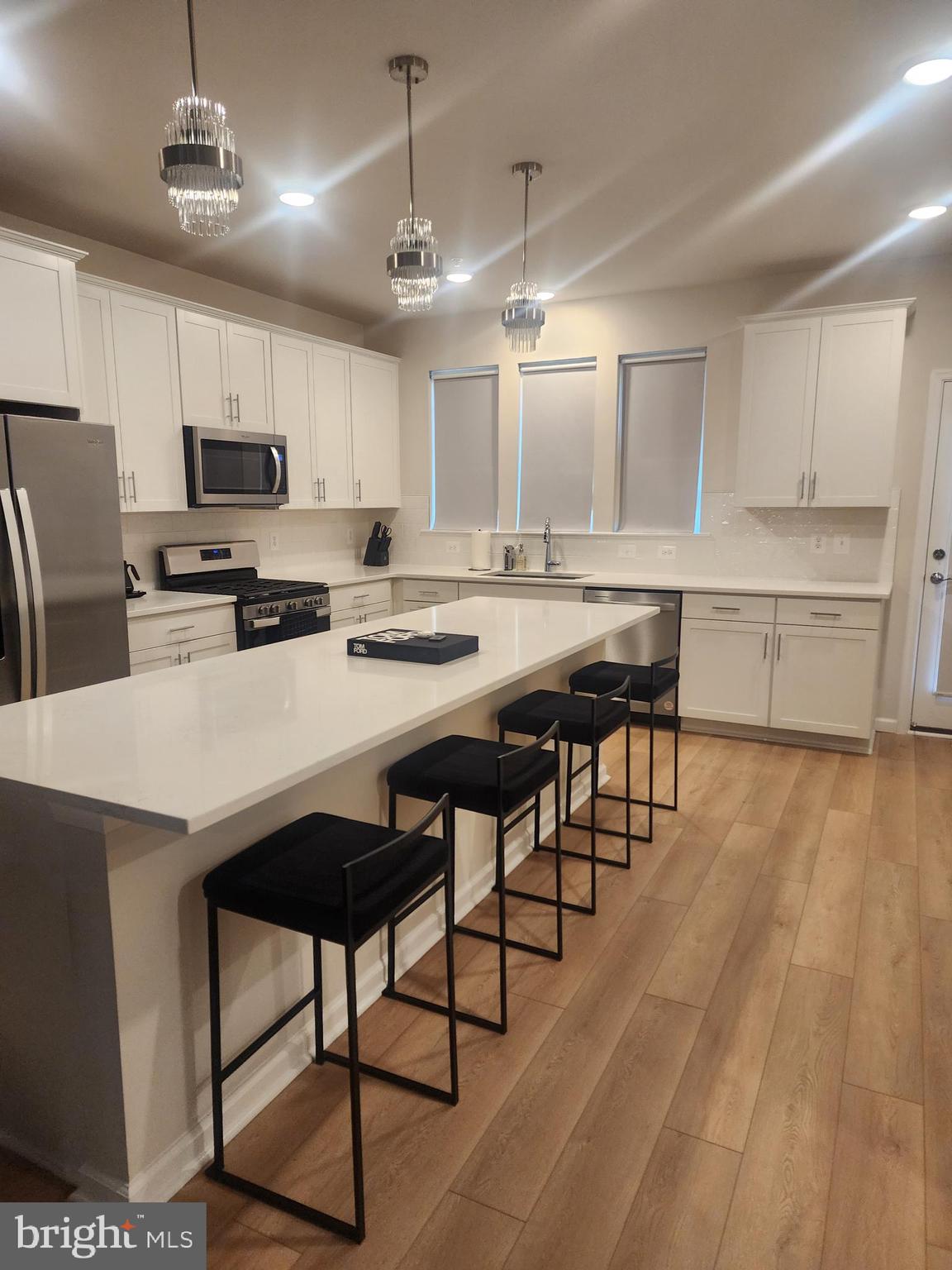 234 Mainstream Drive Laurel, MD 20724 - Photo 18 of 40 a kitchen with stainless steel appliances granite countertop a stove a refrigerator a sink a dining table and chairs with wooden floor