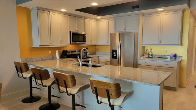 a kitchen with granite countertop a table chairs microwave and refrigerator