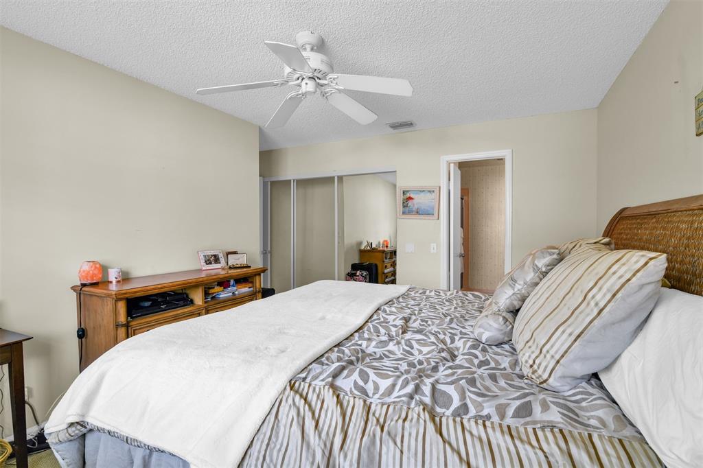 6693 Via Regina, Unit 6693 Boca Raton, FL 33433 - Photo 23 of 27 a bedroom with a bed and a chandelier