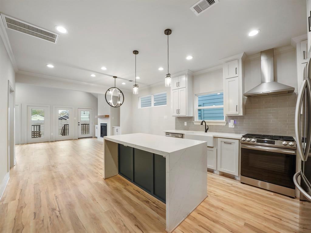a large kitchen with stainless steel appliances a stove a sink a oven and a wooden floors
