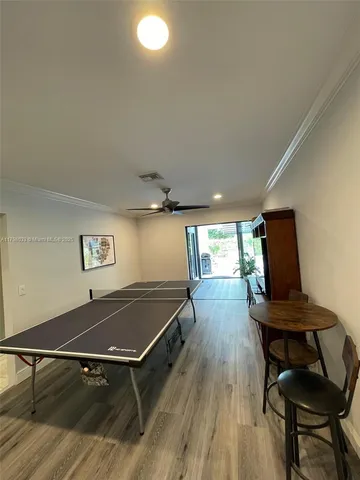 a room with wooden floor pool table chair and windows