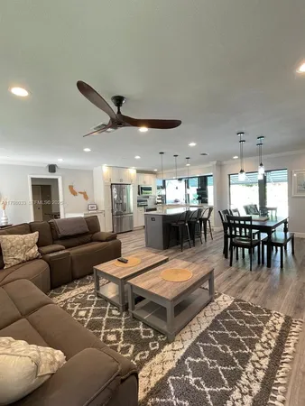 a kitchen with stainless steel appliances granite countertop a stove top oven a sink a dining table and chairs with wooden floor