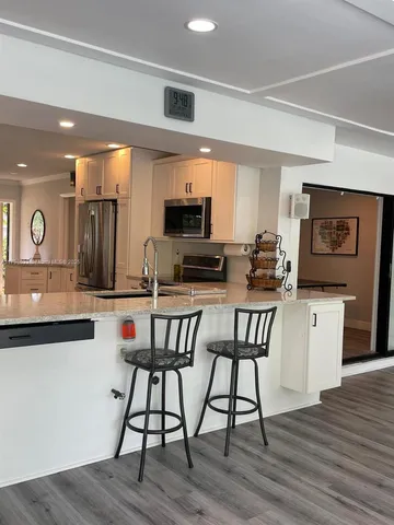 a kitchen with stainless steel appliances granite countertop a stove top oven a sink a dining table and chairs with wooden floor