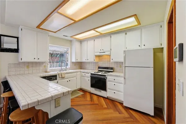 a kitchen with a stove a refrigerator and white cabinets