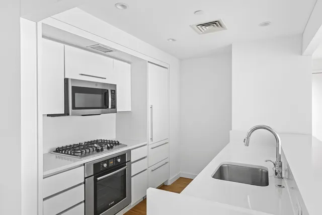 a kitchen with stainless steel appliances granite countertop a sink and a stove top oven with wooden floor