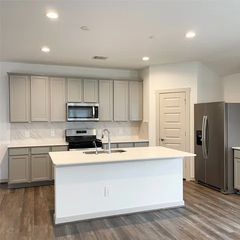 a large kitchen with stainless steel appliances kitchen island a sink dishwasher a refrigerator and a stove with wooden floor