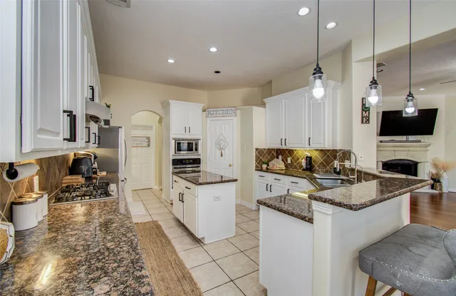 a kitchen with stainless steel appliances kitchen island granite countertop a stove top oven a sink a counter top space and cabinets