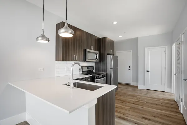 a kitchen with a sink a counter top space stainless steel appliances and wooden floor