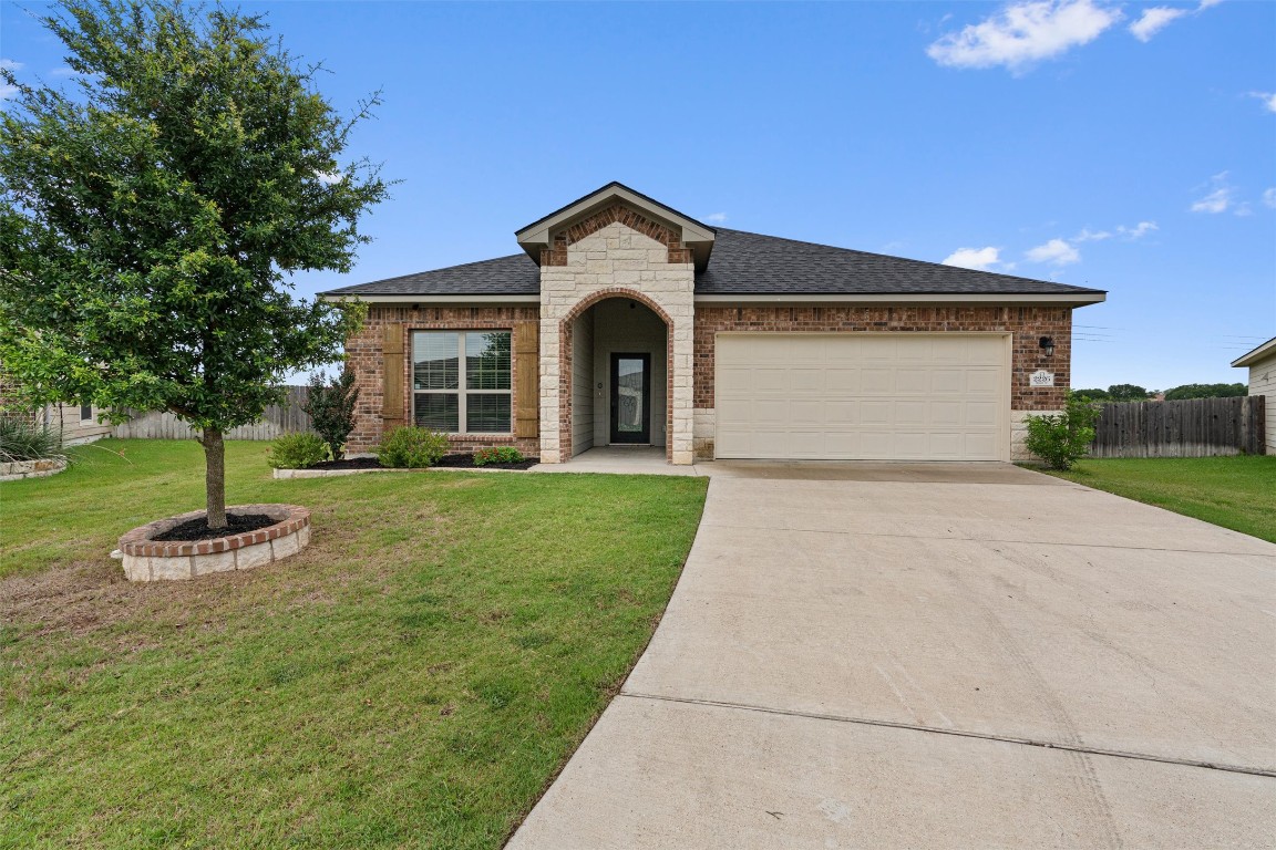 a view of a house with a yard and large tree
