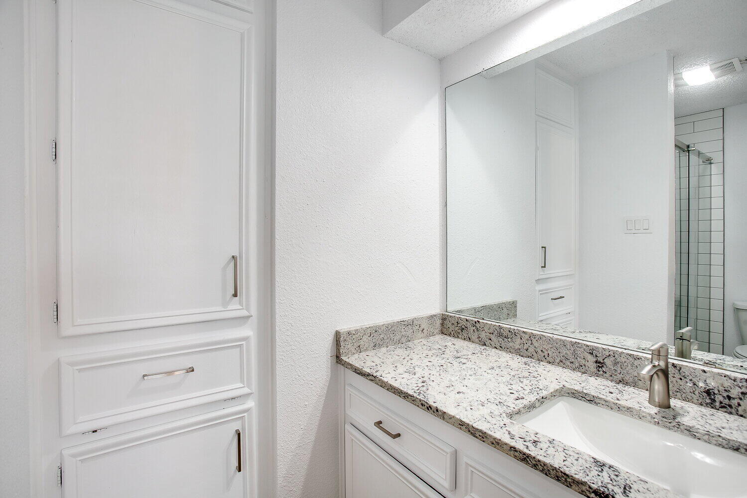 4804 76th Street, Unit A Lubbock, TX 79424 - Photo 22 of 31 a bathroom with a granite countertop sink and white cabinets