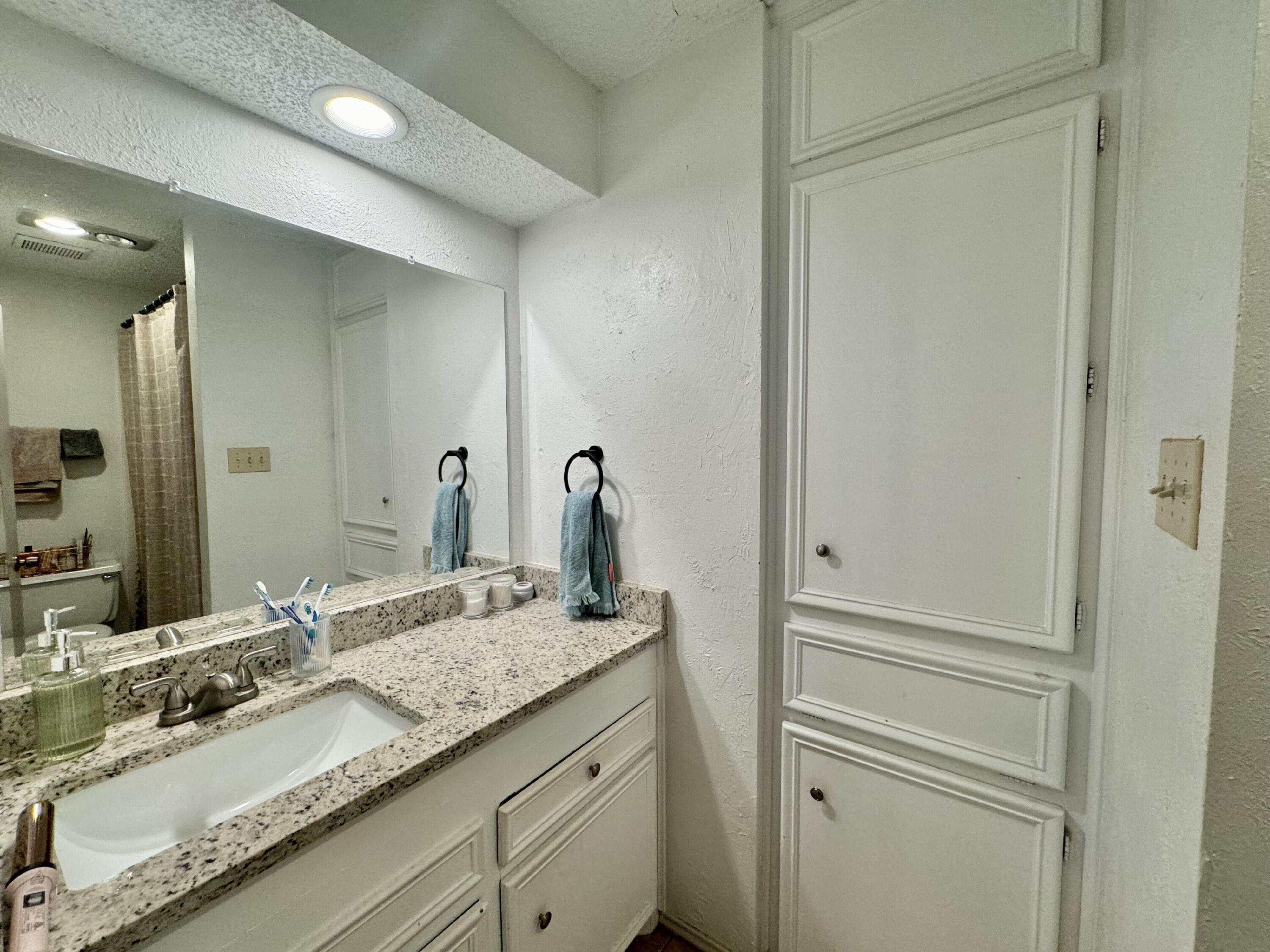 4804 76th Street, Unit A Lubbock, TX 79424 - Photo 25 of 31 a bathroom with a granite countertop sink and a mirror