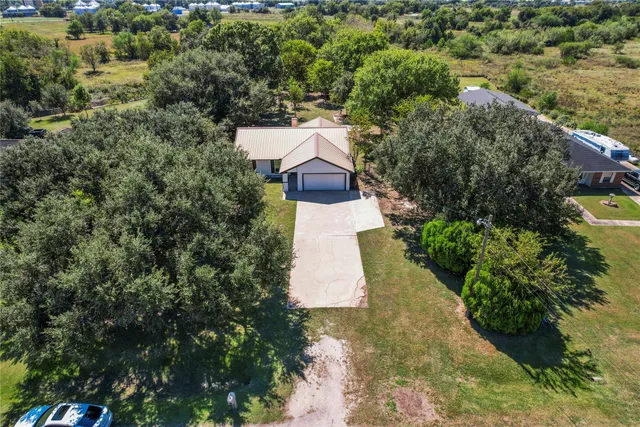 an aerial view of a house with a yard and large trees