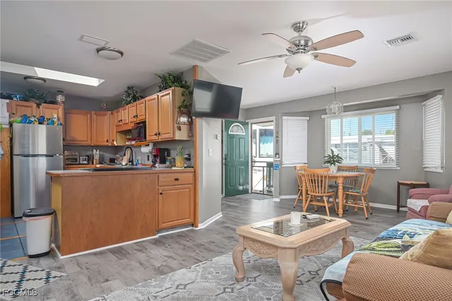 a kitchen with stainless steel appliances kitchen island granite countertop a refrigerator a stove a sink with a dining table and chairs with wooden floor