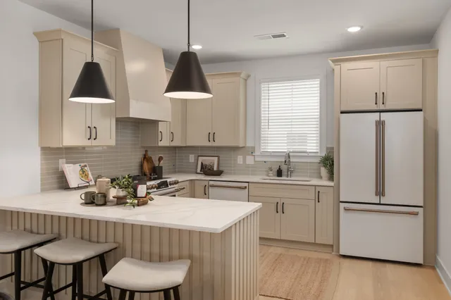 a kitchen with stainless steel appliances granite countertop a sink a stove a refrigerator and island with wooden floor