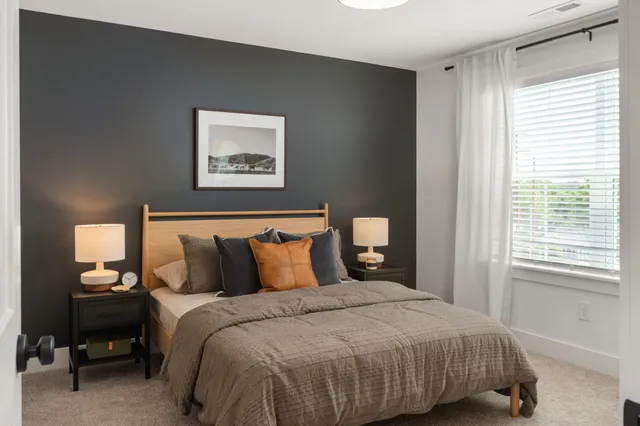 a bedroom with a bed and a lamp on dresser