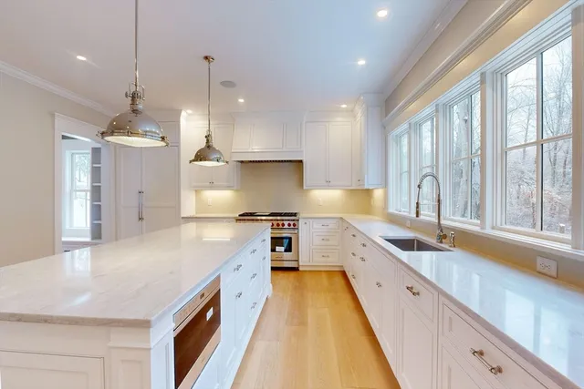 a large kitchen with kitchen island a large counter space a sink appliances and a large window