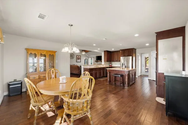 a kitchen with stainless steel appliances granite countertop a refrigerator a stove a sink and a dining table with wooden floor