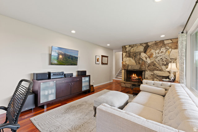 3320 Cherokee Lane Provo, UT 84604 - Photo 9 of 52 Living area featuring a stone fireplace with a metal screen, wood-finish flooring, recessed lighting, and a large window with patterned drapes