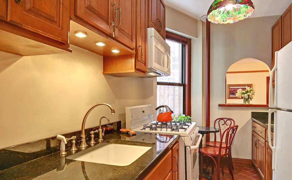 170 East 94th Street, Unit 5E Manhattan, NY 10128 - Photo 6 of 8 a kitchen with a table chairs stove and kitchen island