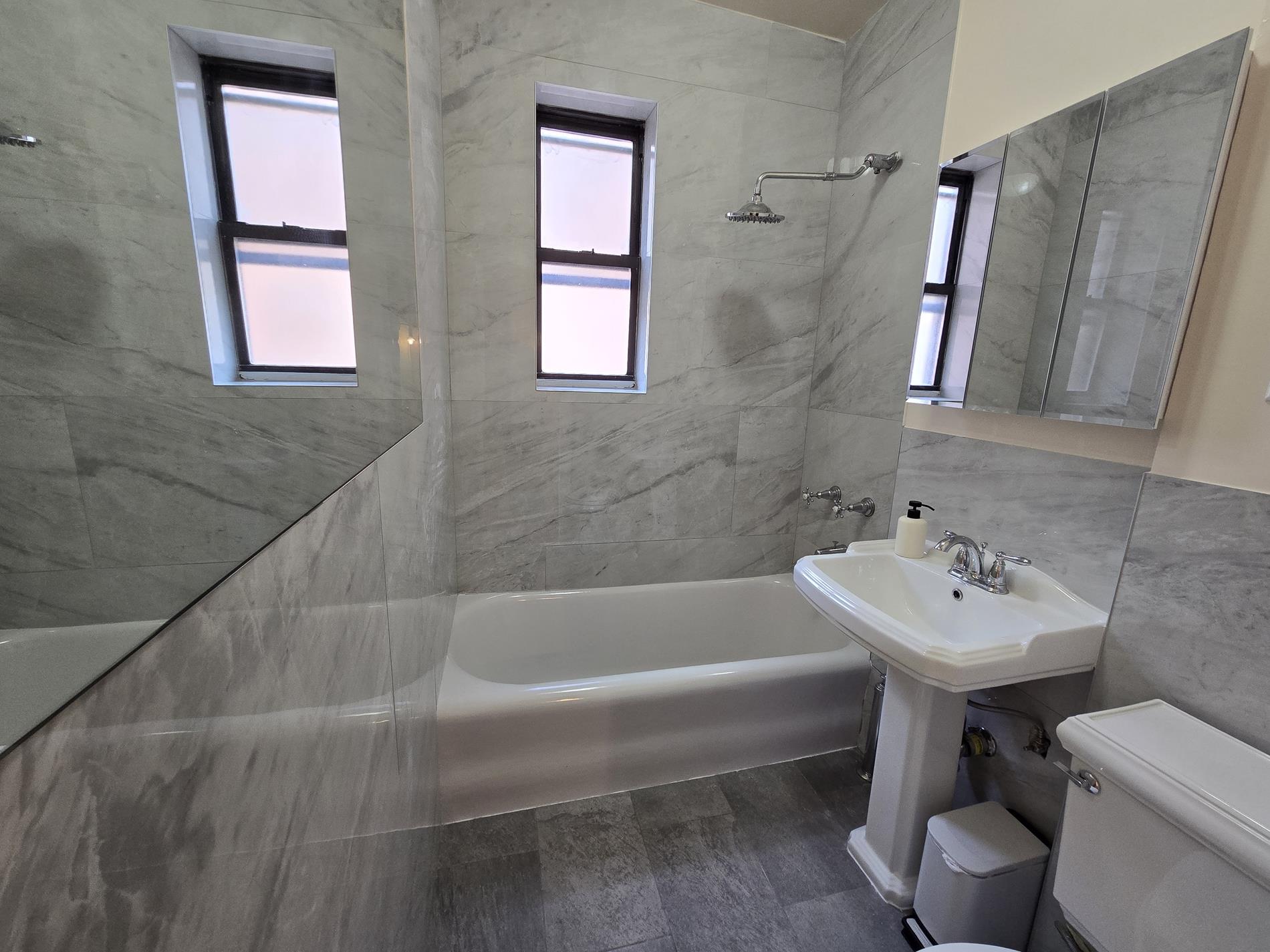 170 East 94th Street, Unit 5E Manhattan, NY 10128 - Photo 7 of 8 a bathroom with a sink a toilet and tub