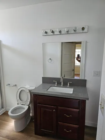 a bathroom with a granite countertop toilet sink and mirror