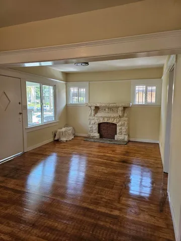 a view of empty room with wooden floor and fireplace