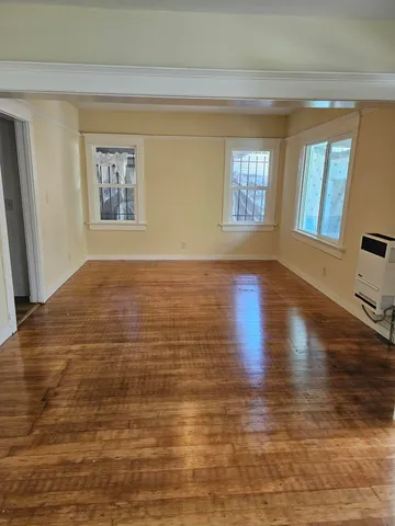 a view of an empty room with window and wooden floor