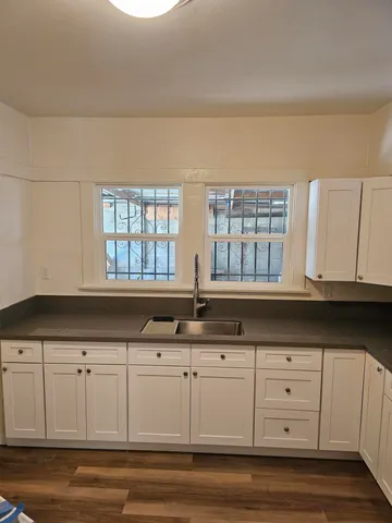 a kitchen with granite countertop white cabinets and a window