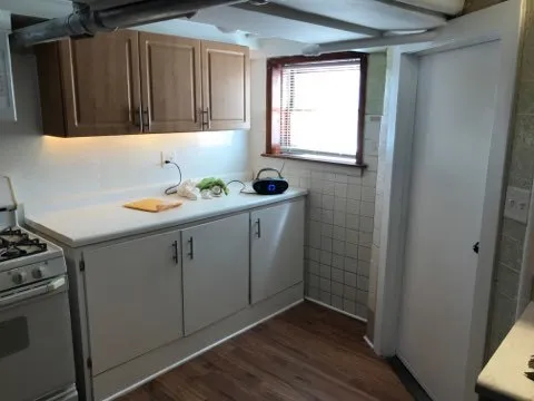 a kitchen with a sink a stove cabinets and wooden floor