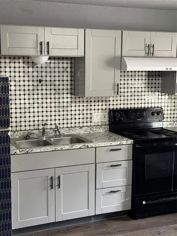 a kitchen with granite countertop a stove cabinets and wooden floor