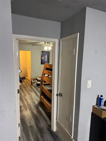 a view of a hallway with wooden floor and bedroom with wooden floor