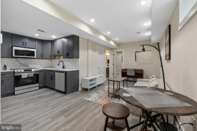 a kitchen with stainless steel appliances granite countertop a stove top oven a sink dishwasher a dining table and chairs with wooden floor